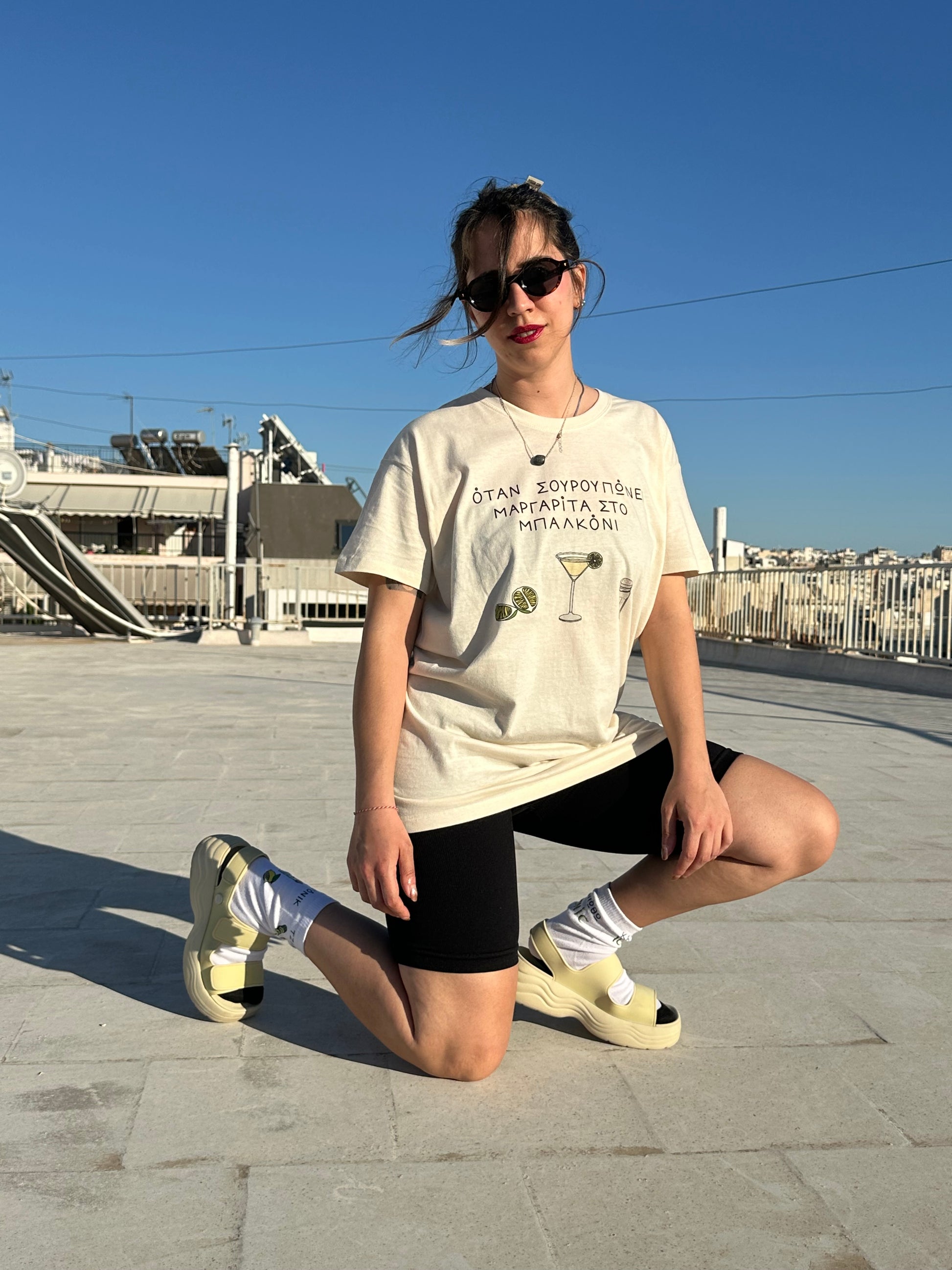 Person sitting on a wall with a clear blue sky and urban background