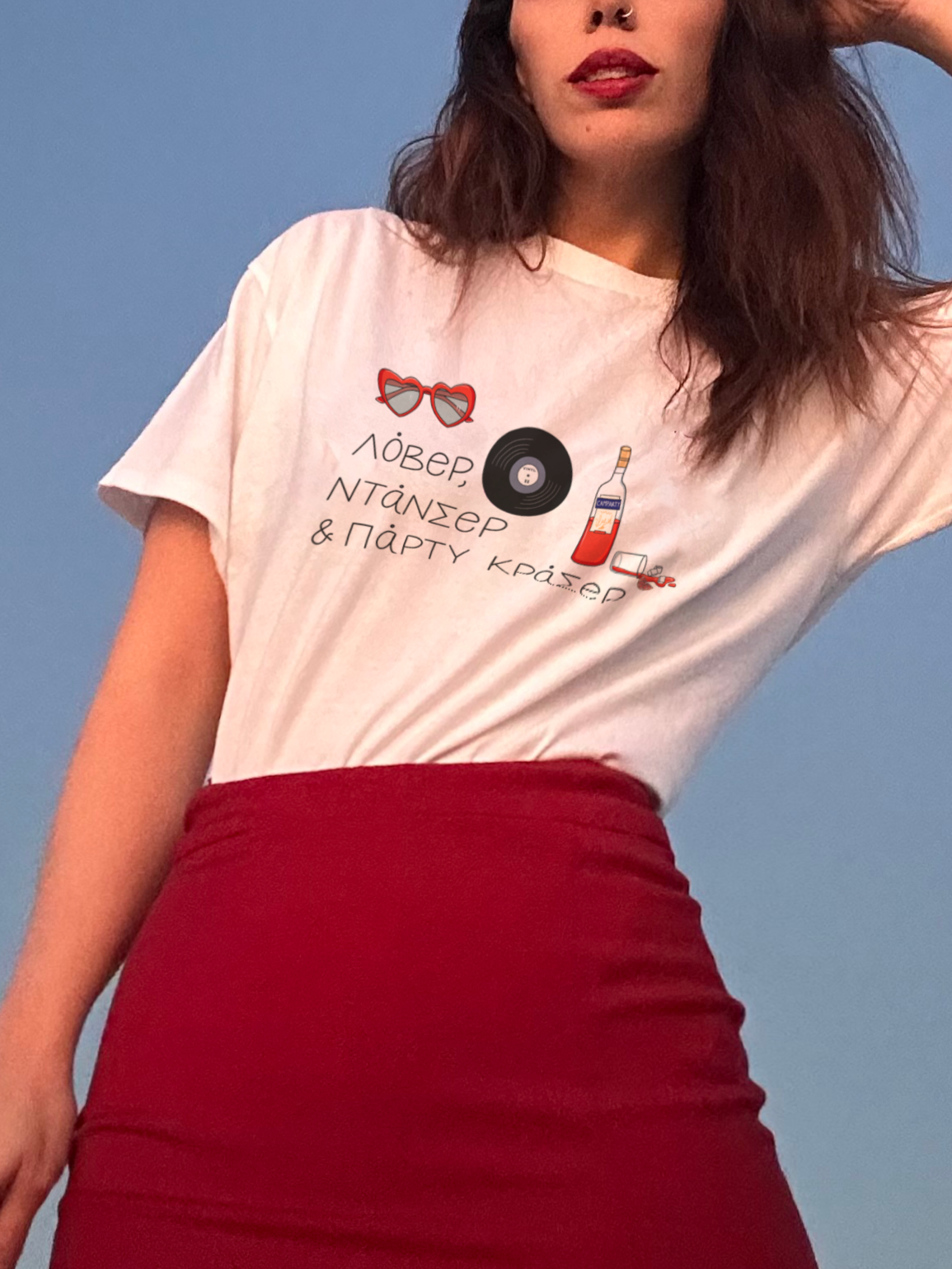 A girl wearing a white crew neck t-shirt with a printed design that includes text and an illustration of a vinyl record, displayed against a blue background. The t-shirt is paired with a red skirt.
