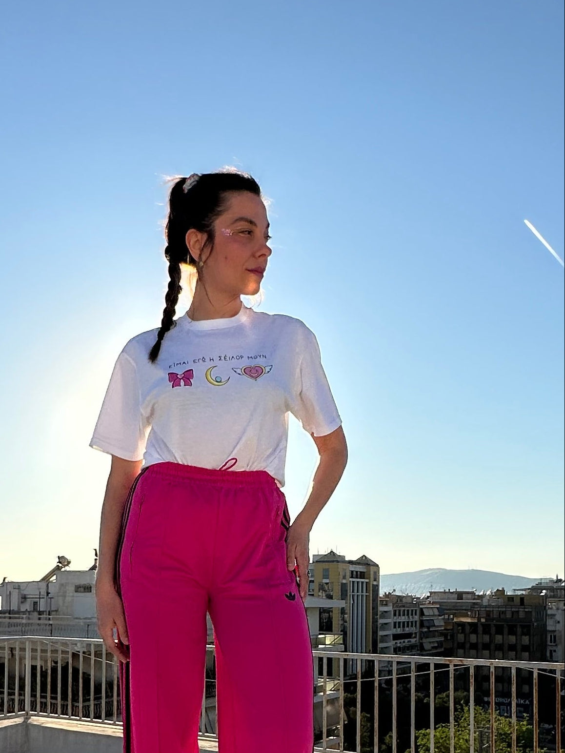 Person standing on a sunlit sidewalk with buildings in the background