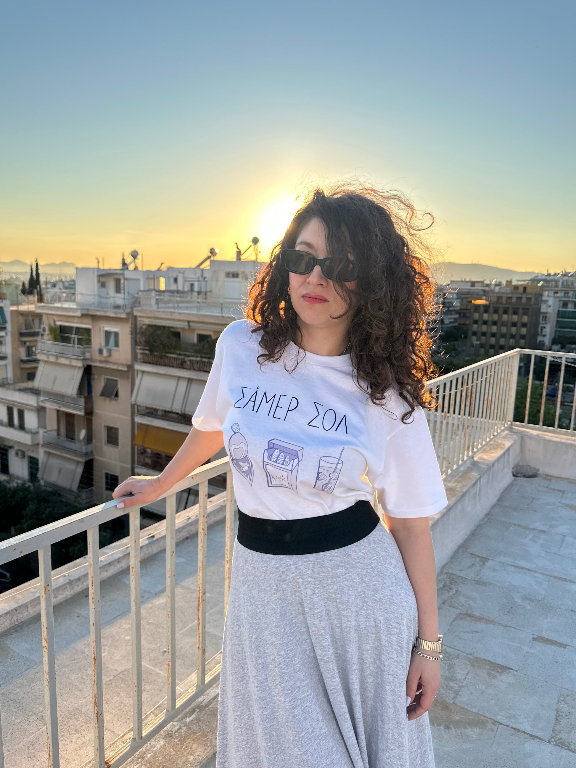 Woman standing on a rooftop with a cityscape background during sunset.