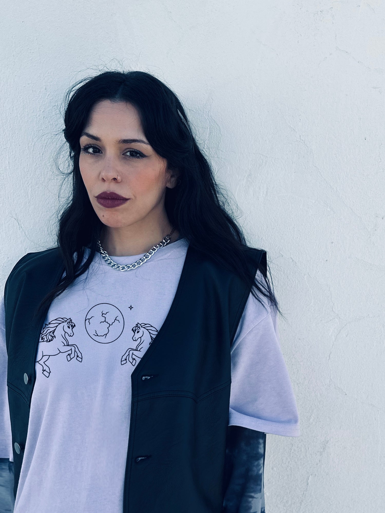 Woman wearing a white t-shirt with black designs against a white wall
