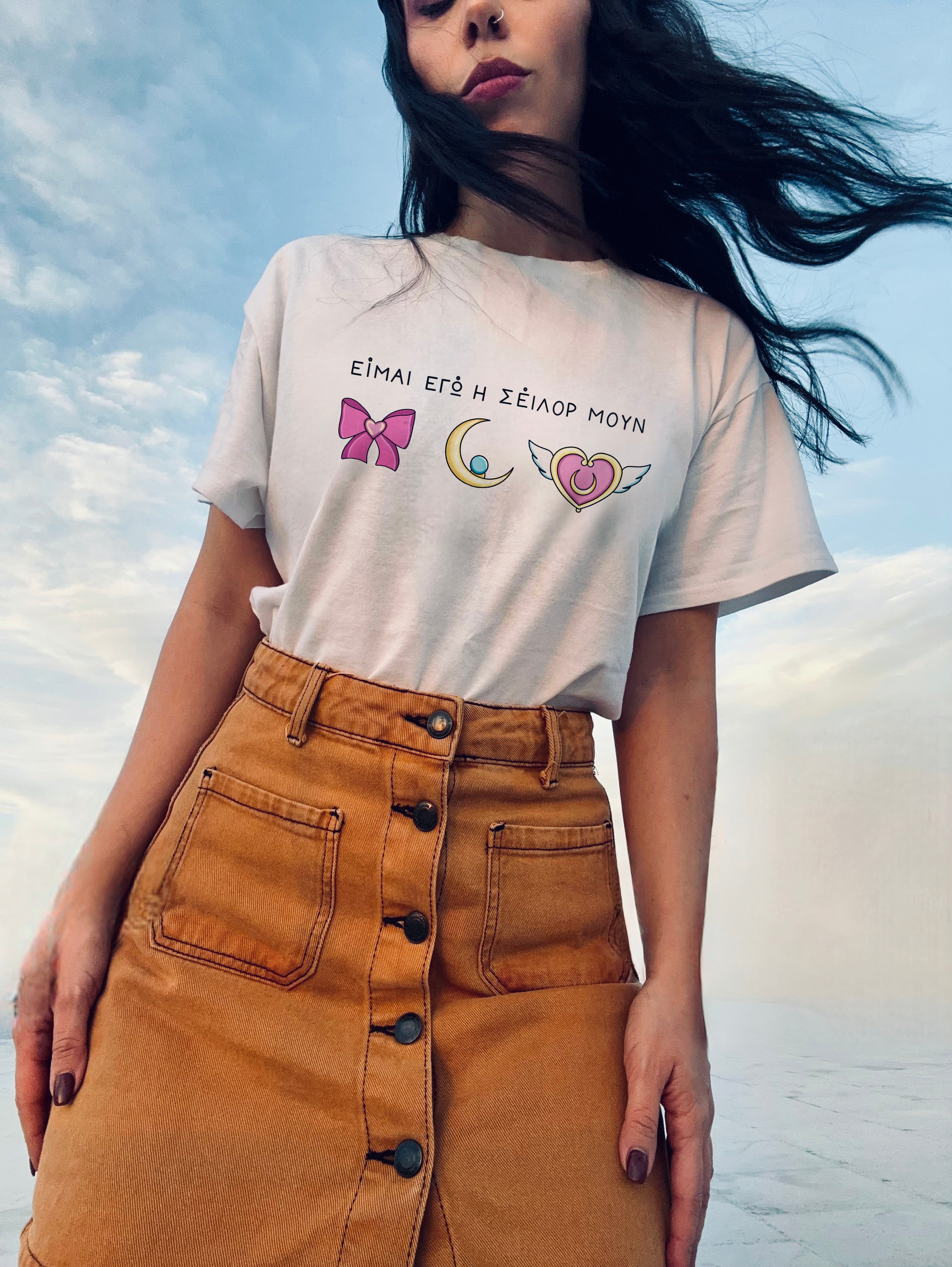 Person wearing a white t-shirt with graphics and text, standing against a sky background